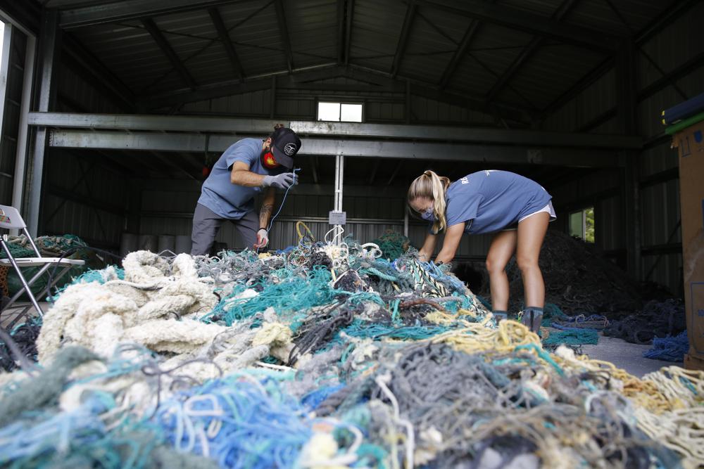 Two researchers detangle a large pile of derelict fishing gear at the original net shed.